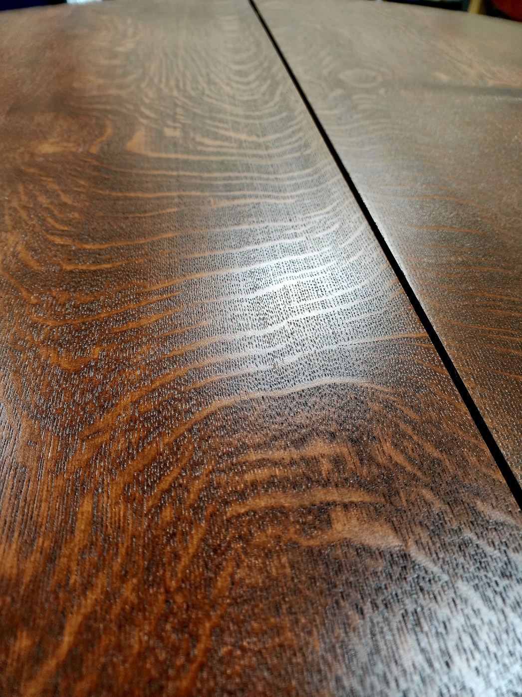 Close-up of a refinished dark oak tabletop showing detailed grain patterns.