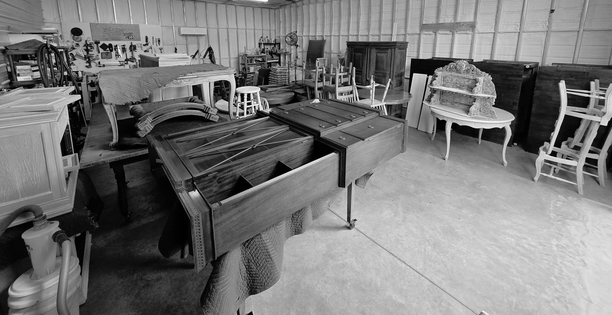 Furniture refinishing workshop with antique tables and chairs.