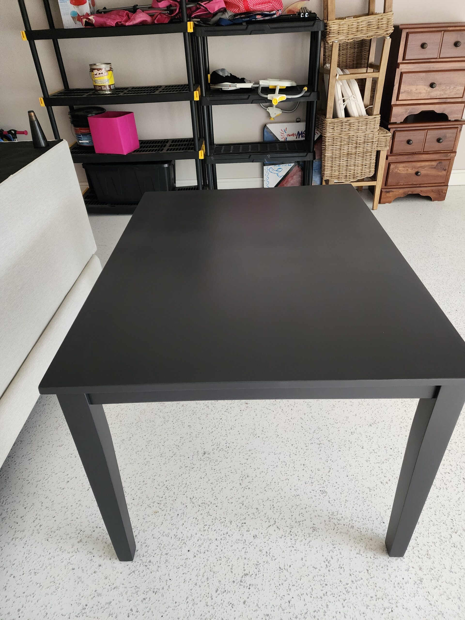 Wood dining table refinished in a smooth matte black finish.
