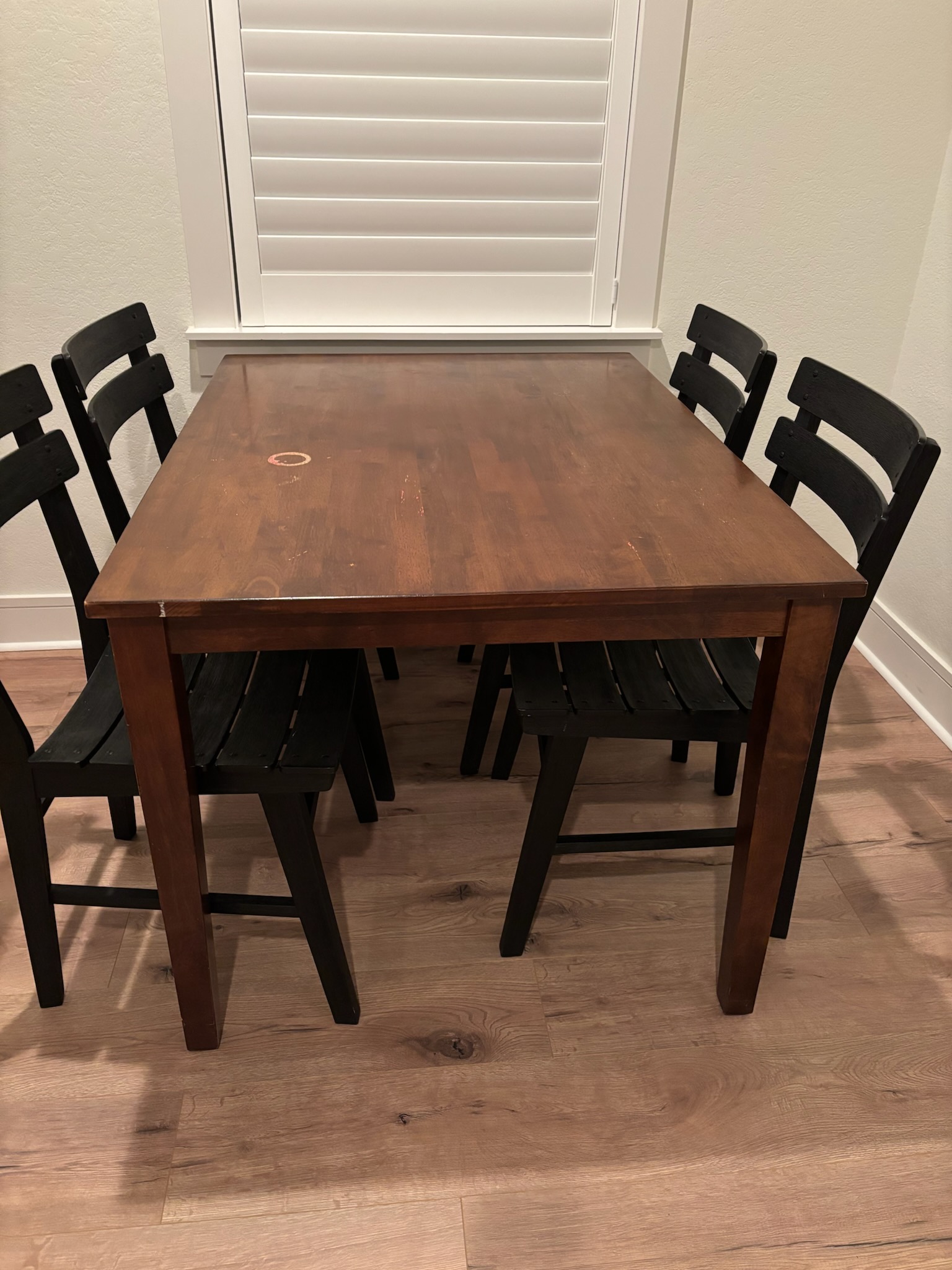 Wood dining table with visible finish wear and water rings.