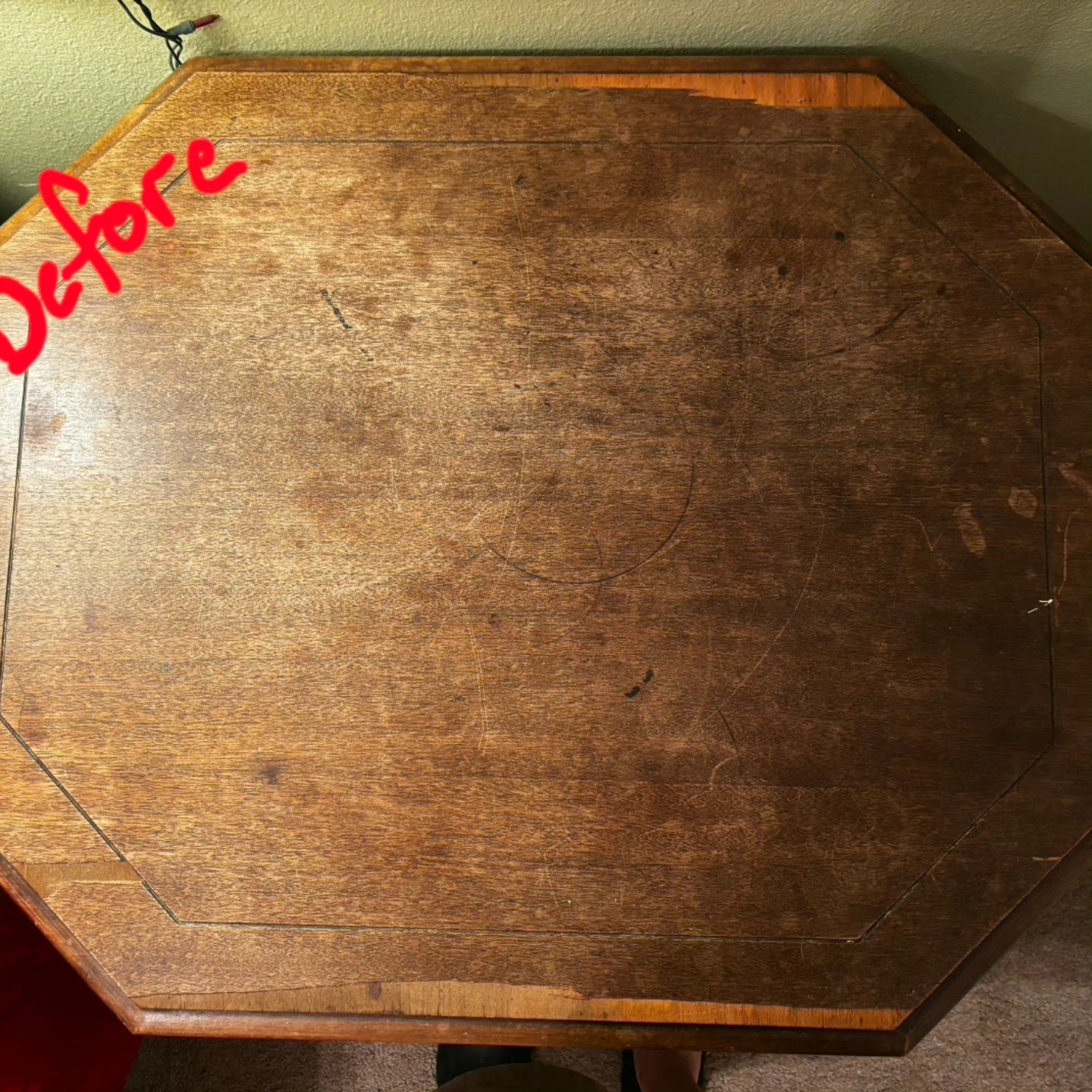 Octagonal wooden table with worn finish and surface damage.