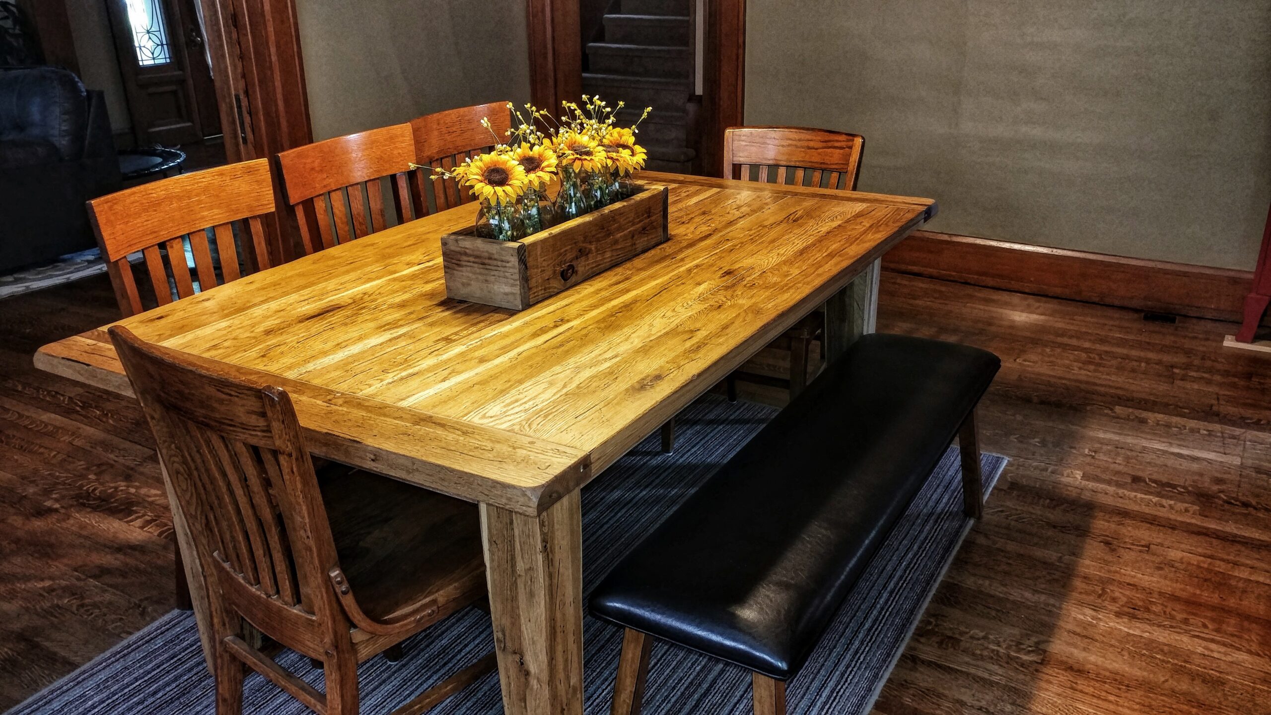 Rustic solid wood farmhouse dining table with bench and chairs restored with a warm natural finish.